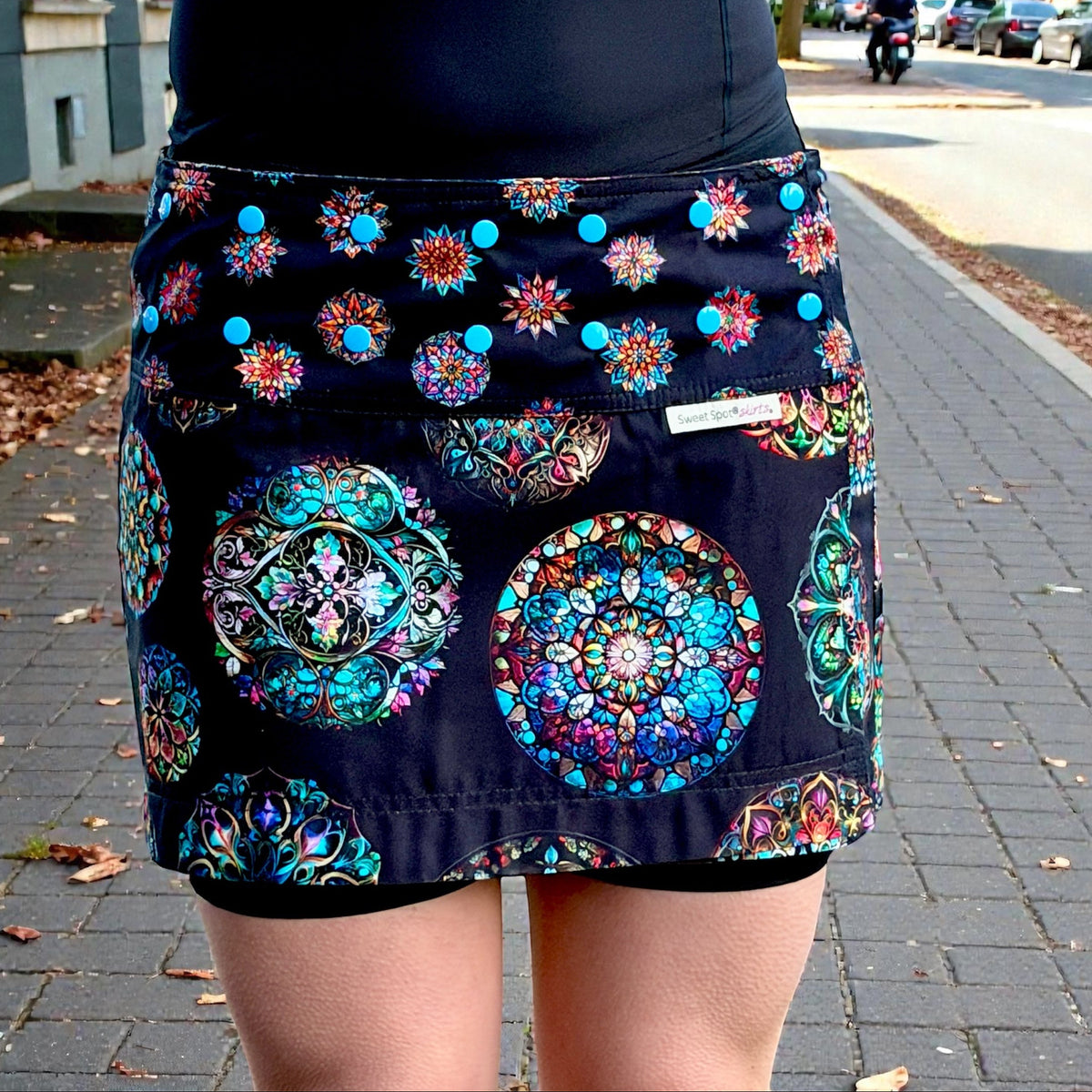 Person wearing a navy blue skirt with colorful geometric patterns on a street.